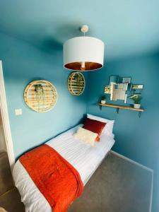 a blue room with a bed with an orange blanket at Coastal 2 bedroom maisonette with parking in Eastbourne