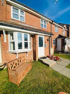 a wooden bench in front of a brick house at Coastal 2 bedroom maisonette with parking in Eastbourne