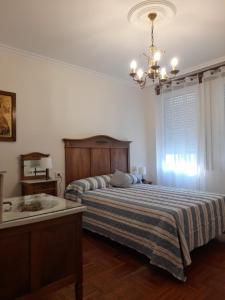 1 dormitorio con cama, lavabo y lámpara de araña en XOAN DE REQUEIXO, en Chantada