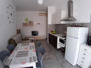 a kitchen with a table and a white refrigerator at CASA ALEXSA Intero appartamento o CAMERA ALEXSA Camera matrimoniale con patio in Tortolì