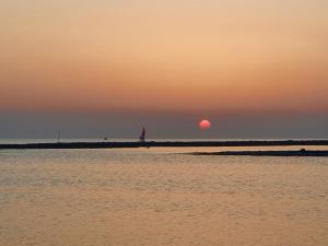 a sunset over the water with a sailboat in the distance at Villa Sette Nani in Torre Lapillo