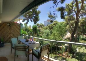 アテネにあるA7 Beauty Vouliagmeni Apt in a unique Spotの木々が植わるバルコニー(テーブル、椅子付)