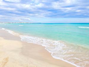 a beach with the ocean and a cloudy sky at Villa Sette Nani in Torre Lapillo