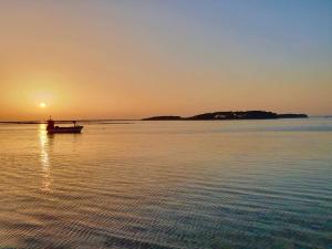 a man in a boat on the water at sunset at Villa Sette Nani in Torre Lapillo