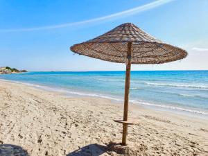 a straw umbrella sitting on a sandy beach at Villa Sette Nani in Torre Lapillo