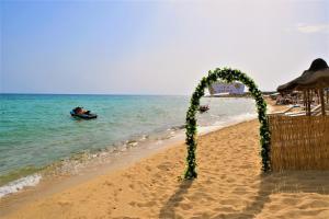 a wedding arch on the beach with a boat in the water at Villa Sette Nani in Torre Lapillo