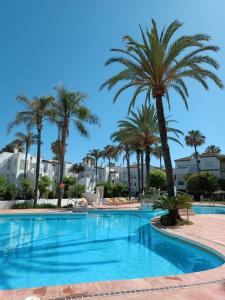 una piscina con palmeras y edificios en Espectacular apartamento primera linea de playa - Golf en Estepona