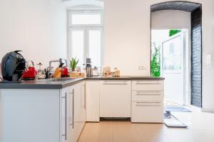 cocina con armarios blancos y ventana grande en homebydoni - Küche I Terrasse I 1000 Mbits WiFi I Design Loft nahe RMCC & Staatstheater, en Wiesbaden