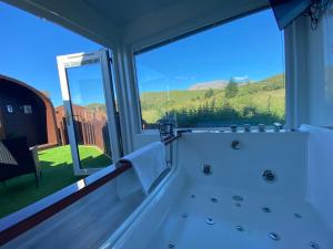 a bath tub in a room with a large window at Highland Stays - Ben View Studio Pod & Jacuzzi Bath in Fort William