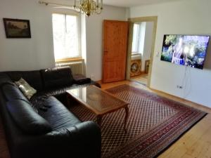 a living room with a black leather couch and a coffee table at Ferienwohnung mit Charme in Dresden Pillnitz EG in Dresden
