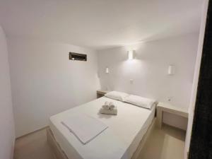 a white bedroom with a bed with a pair of slippers at Family Villages Santorini in Vlychada Beach