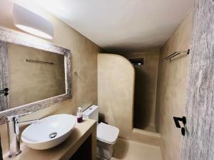 a bathroom with a sink and a toilet and a mirror at Family Villages Santorini in Vlychada Beach