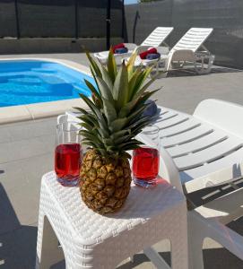 eine Ananas auf einem Tisch mit zwei Gläsern Rotwein in der Unterkunft Apartments Ukic - with large outdoor pool in Kaštela