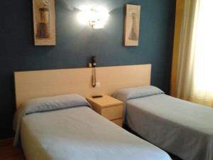 2 łóżka w pokoju z niebieskimi ścianami w obiekcie Hotel Luzon w mieście San Vicente de la Barquera