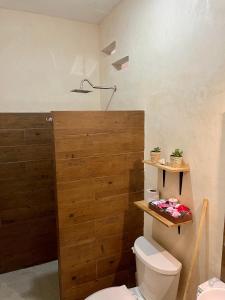 ein Badezimmer mit einem WC und einer Holztür in der Unterkunft Estudios Rehilete in Holbox