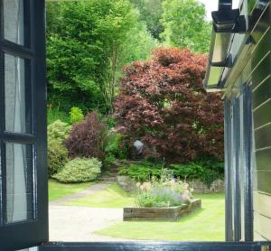 uma janela com vista para um jardim a partir de uma casa em The Annexe @Granny’s Apple Lodge em Blakeney