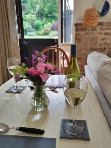 uma mesa com uma garrafa de vinho e um vaso de flores em The Annexe @Granny’s Apple Lodge em Blakeney