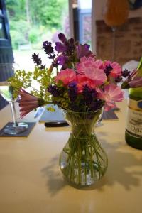 a glass vase filled with flowers on a table at The Annexe @Granny’s Apple Lodge in Blakeney