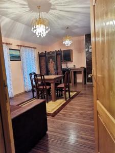 una sala da pranzo con tavolo, sedie e lampadari a braccio di Apartmani Vojinović a Sjenica