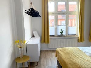 a bedroom with a bed and a window with yellow curtains at Lovely City-Apartment*Tiefgarage,Zentrum,BTU* in Cottbus