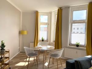 - un salon avec une table, des chaises et 2 fenêtres dans l'établissement Lovely City-Apartment*Tiefgarage,Zentrum,BTU*, à Cottbus