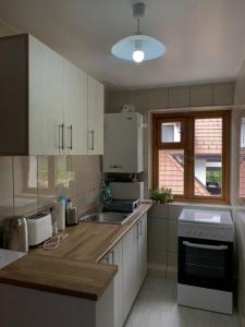 een keuken met witte kasten, een wastafel en een raam bij Belle View Apartment Sinaia in Sinaia
