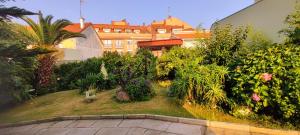 un jardín con plantas y un edificio de fondo en Pisos Vistalegre 2A con jardín tranquilos cerca del mar, en Sanxenxo