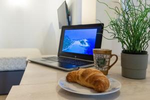 a plate with a croissant on a table with a laptop computer at Casa Vacanza Home MAF in Cagliari