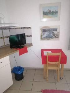 a kitchen with a desk with a red table and a television at Pension Egida in Řež