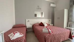 a bedroom with two beds with red sheets and a mirror at L’Angolo Chiaro in Taviano