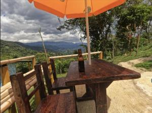 a bottle of beer sitting on a wooden table with an umbrella at Eco Cabaña en el Campo in La Vega