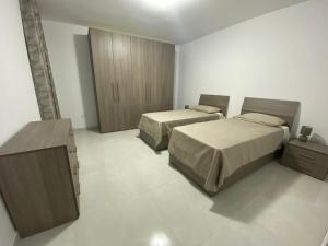 a bedroom with two beds and a wooden cabinet at Modern, Spacious, 3 Bedroom Apartment near Malta International Airport in Luqa