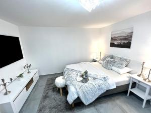 a white bedroom with a bed and a tv at Apartmány Ellie in Znojmo