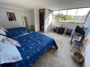 Un dormitorio con una cama azul y un televisor. en CasaHotel Laguna Jauja Airport en Jauja