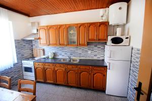 a kitchen with wooden cabinets and a white refrigerator at The Peaceful Vacation in Metajna