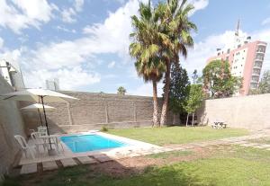 a swimming pool with an umbrella and a palm tree at Departamentos Kairos H in Mendoza