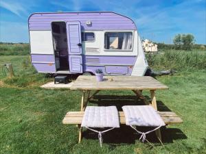 a picnic table and a purple and white trailer at Het Caravannetje B&B - retro glamping in Leidschendam