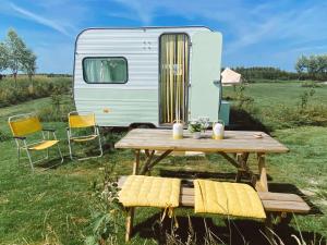 a picnic table and chairs next to a caravan at Het Caravannetje B&B - retro glamping in Leidschendam