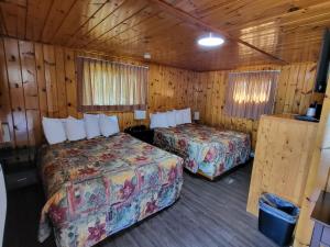 two beds in a room with wooden walls at Sunset Motel of St. Ignace in Saint Ignace