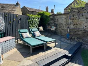 a patio with two chairs and a table at Honeybee Cottage, with a log fire & a hot tub. in Bradford