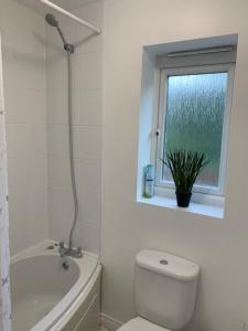 een witte badkamer met een toilet en een raam bij Spacious and central 4-bedroom house with parking in Birmingham