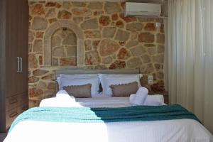 1 dormitorio con 1 cama grande y pared de piedra en Blue Sea House, en Agios Nikolaos