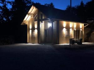 un bâtiment avec des lumières sur son côté la nuit dans l'établissement Forest Jura Lodge - Chalet des sapins, à Alièze