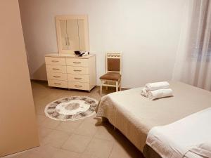 a bedroom with two beds and a dresser and a chair at Sky 2 Apartment City Center in Shkodër