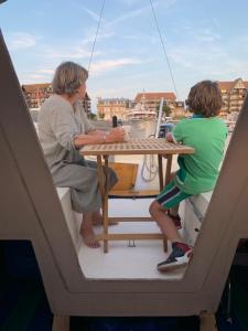 a man and a child sitting at a table on a boat at Madi au fil de l'eau à Deauville in Deauville