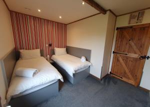 a small room with two beds and a door at Durham Coastal Lodges in Haswell