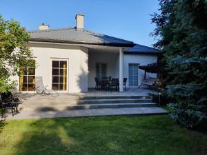 a white house with a patio and a table and chairs at Apartament z Ogrodem in Stanisławów Pierwszy