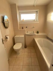 La salle de bains est pourvue de toilettes, d'une baignoire et d'une fenêtre. dans l'établissement Burnt Island 2 bed apartment with stunning views, à Fife