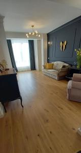 uma ampla sala de estar com um sofá e piso em madeira em Sunny Apart Hereditas em Ipoteşti
