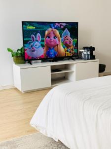 a bedroom with a flat screen tv on a white entertainment center at The apartment near the beach in Oeiras in Paço de Arcos